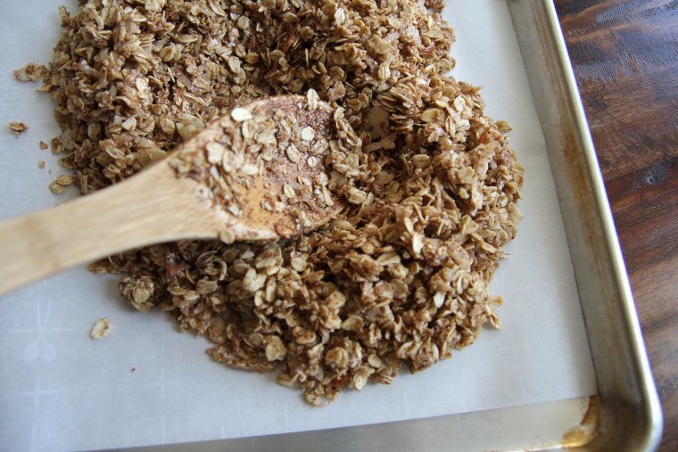 spreading granola on baking sheet