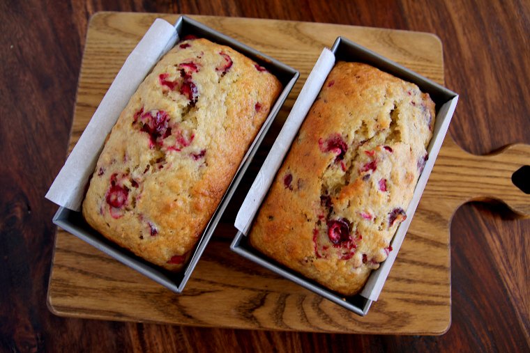 two cranberry banana bread loaves on a cutting board