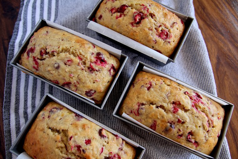 four loaves of cranberry banana bread on a kitchen towel