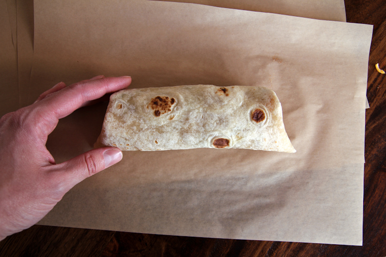 finished breakfast burrito seam-side-down on parchment paper