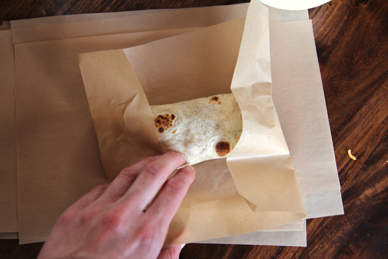 folding ends of parchment paper over the sides of the burrito