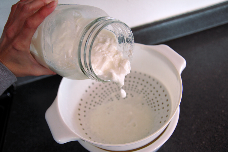 straining kefir into a bowl to remove grains