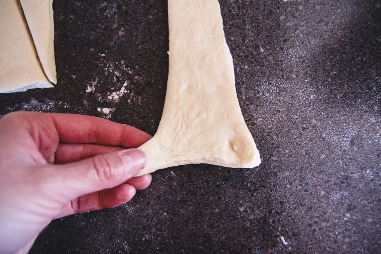 gently stretching the bottom corners of the first triangle before rolling into a croissant