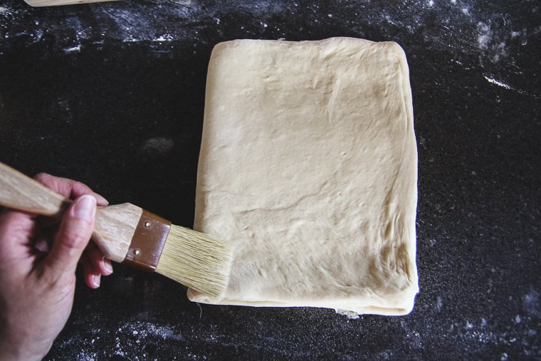 folding the dough in thirds as if folding a letter, brushing away loose flour