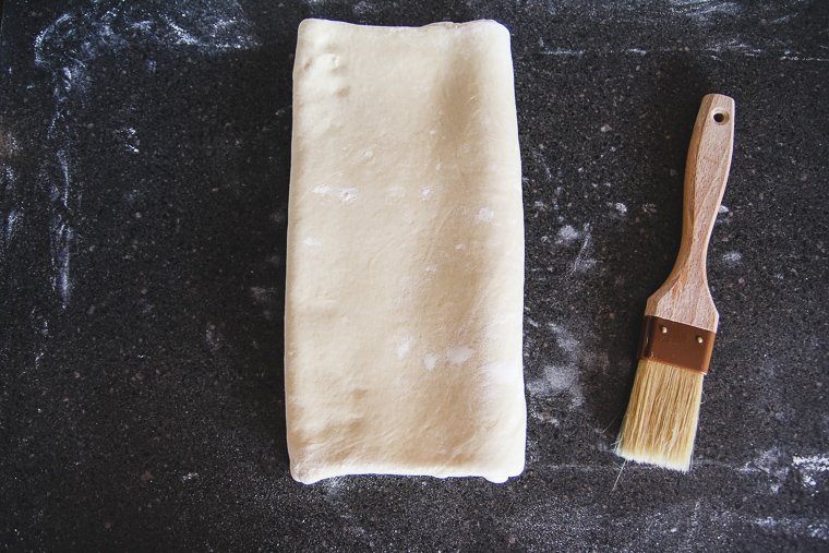 folding the folded ends of the dough together as if closing a book to finish the first lamination fold