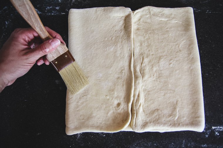 folding the edges of the dough to meet in the middle, brushing away extra flour as I go