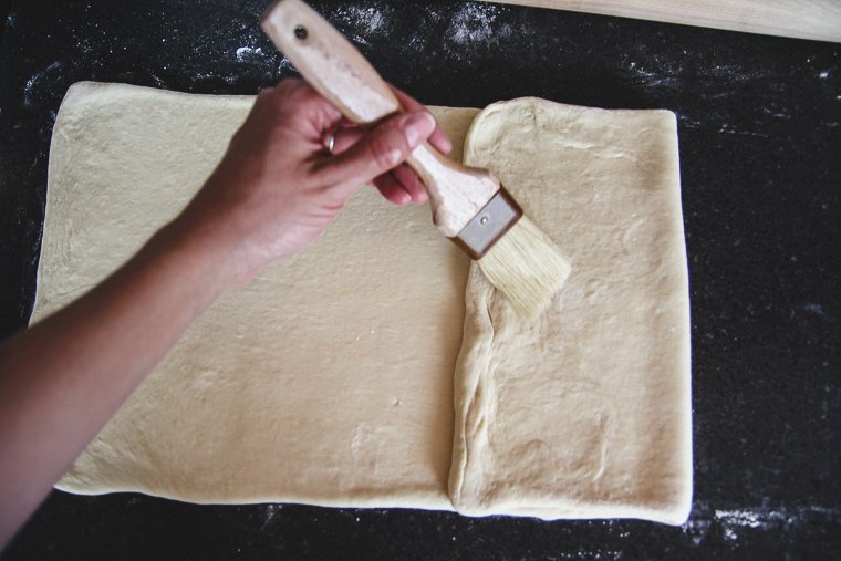 folding the edges of the dough to meet in the middle, brushing away extra flour as I go