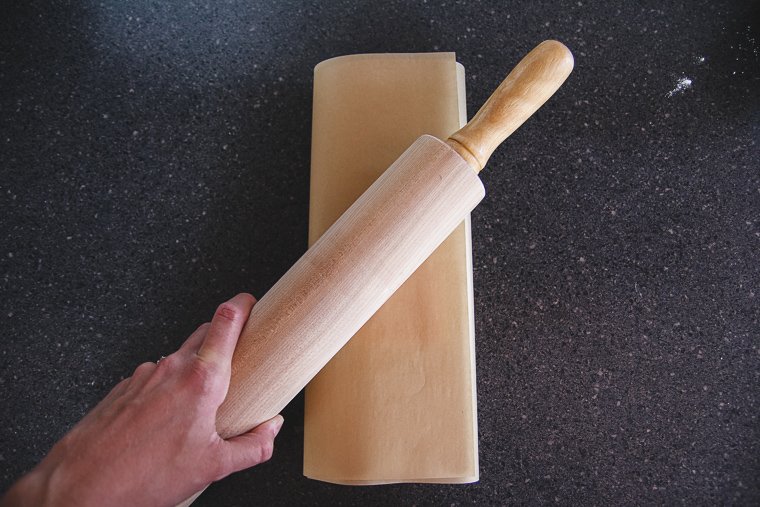 beating the butter with a rolling pin in the parchment paper