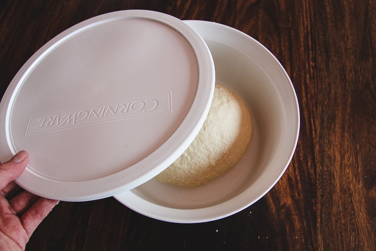 placing dough in a lidded bowl for fermentation