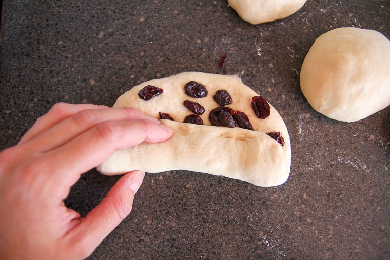rolling the dough up into a log shape to encase the dried blueberries