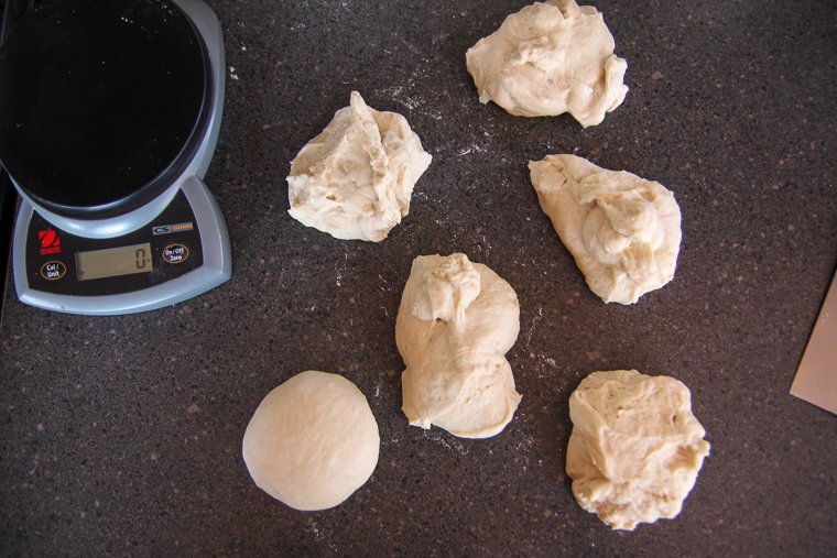 a kitchen scale shown next to 6 pieces of bagel dough