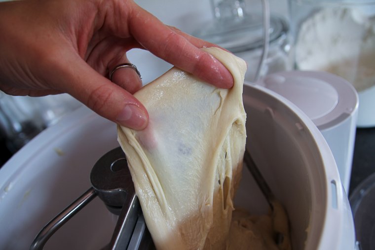 stretching the dough to see if it passes the windowpane test