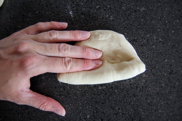 beginning to roll the piece into a little log, pressing the dough down as I go