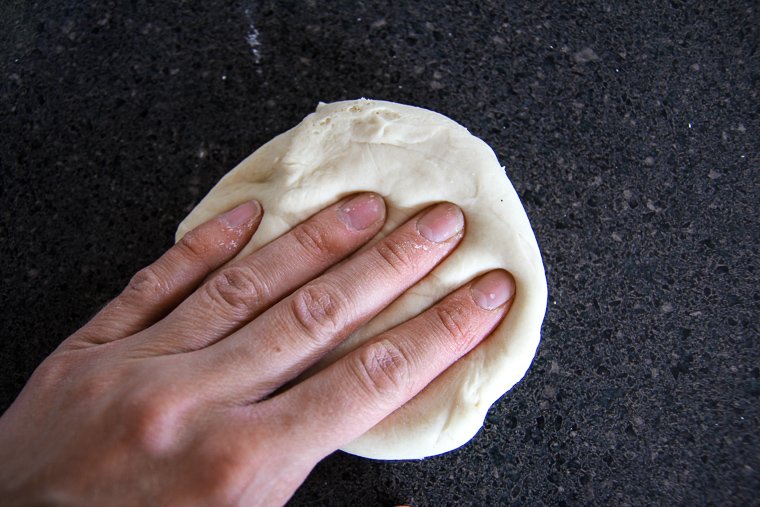 degassing a piece of dough to begin preshaping