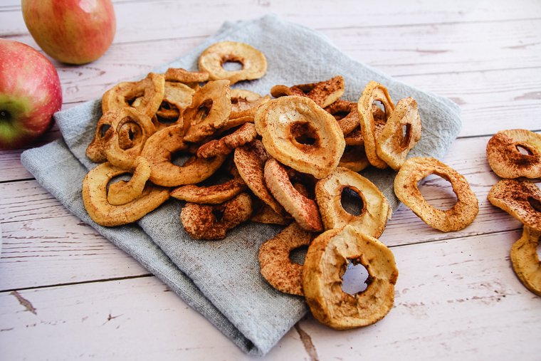 dehydrated apples on a blue napkin next to two apples