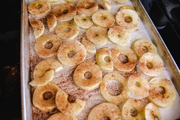 sliced apple rings sprinkled with ground cinnamon and arranged on a parchment-lined baking sheet