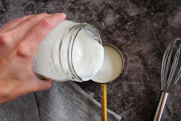 pouring some homemade buttermilk into a measuring cup