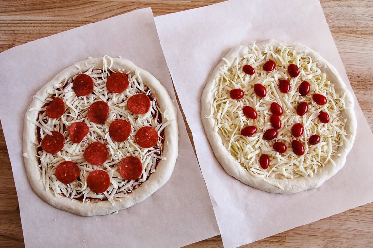 two sourdough pizzas topped and ready for the oven