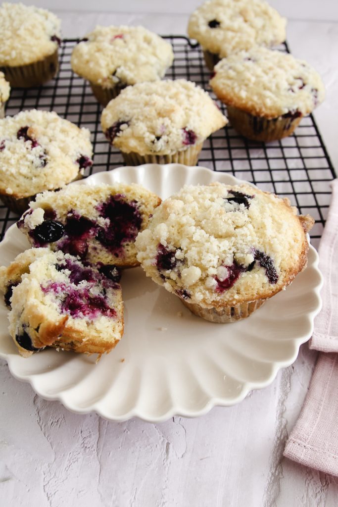 blueberry streusel muffins shown on a plate with one sliced in half