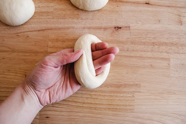 wrapping dough around the back of the hand to make the bagel shape