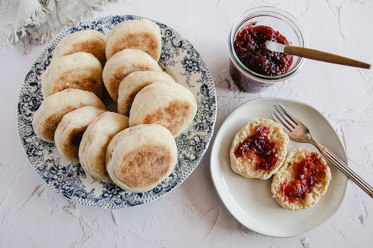 sourdough english muffins next to a muffin with butter and jam
