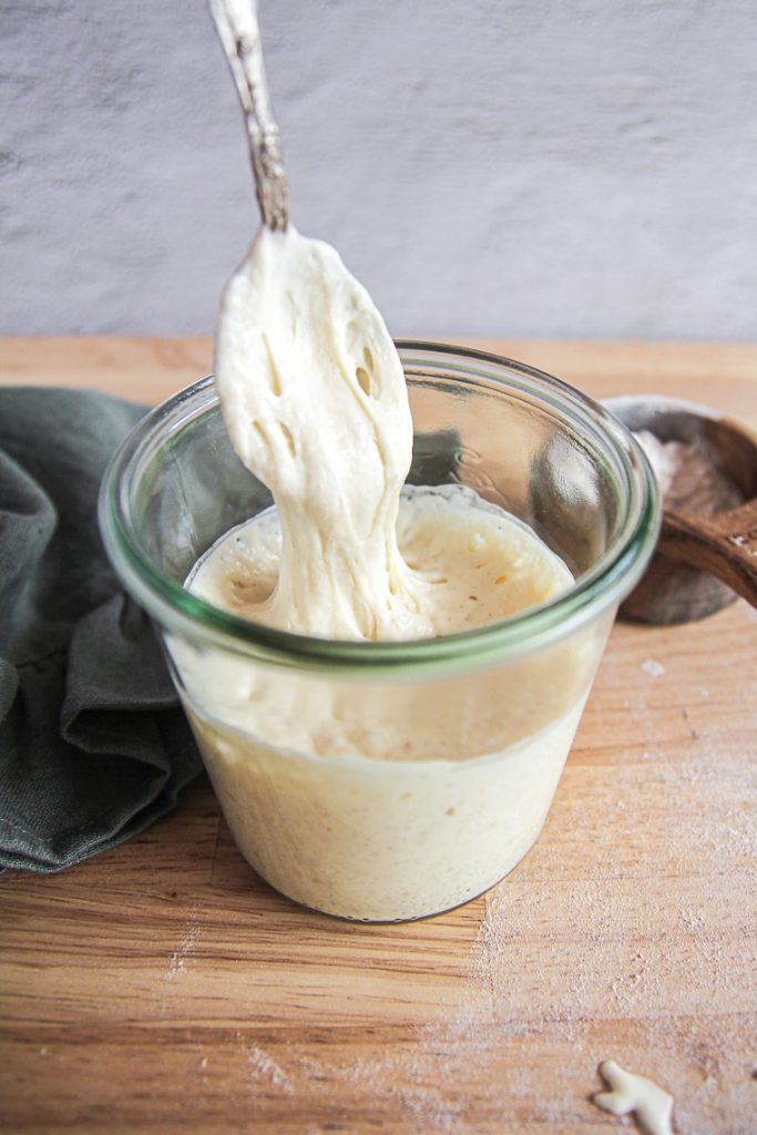 taking out a spoonful of active sourdough starter from a jar