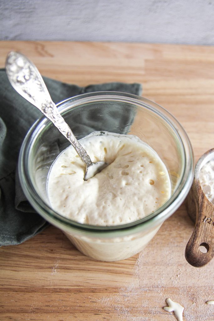 a jar of ripe homemade sourdough starter with a spoon