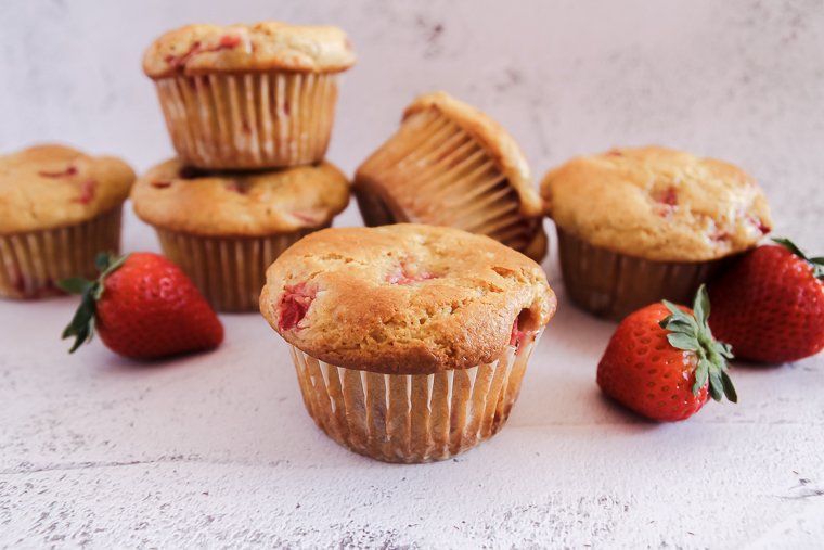 strawberry whole wheat and millet muffins arranged next to fresh strawberries