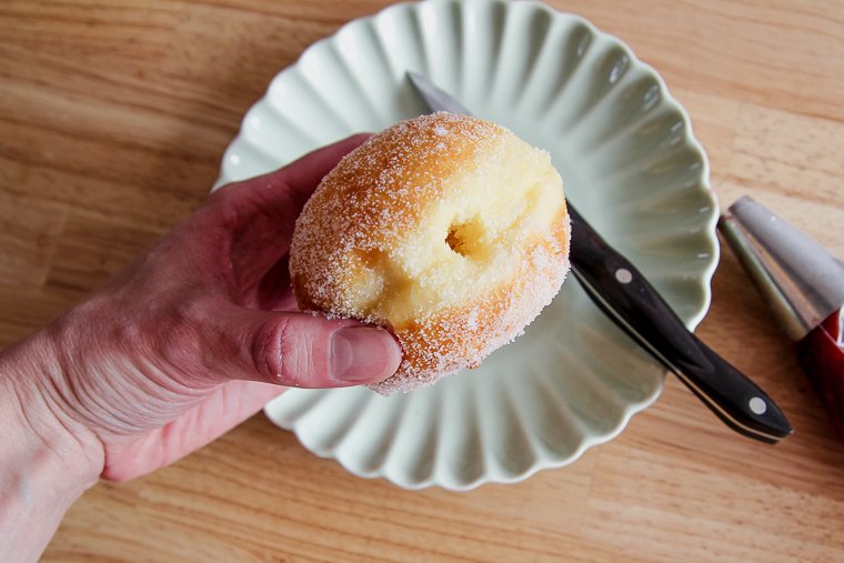 piercing the donut with a pairing knife to make room for the filling