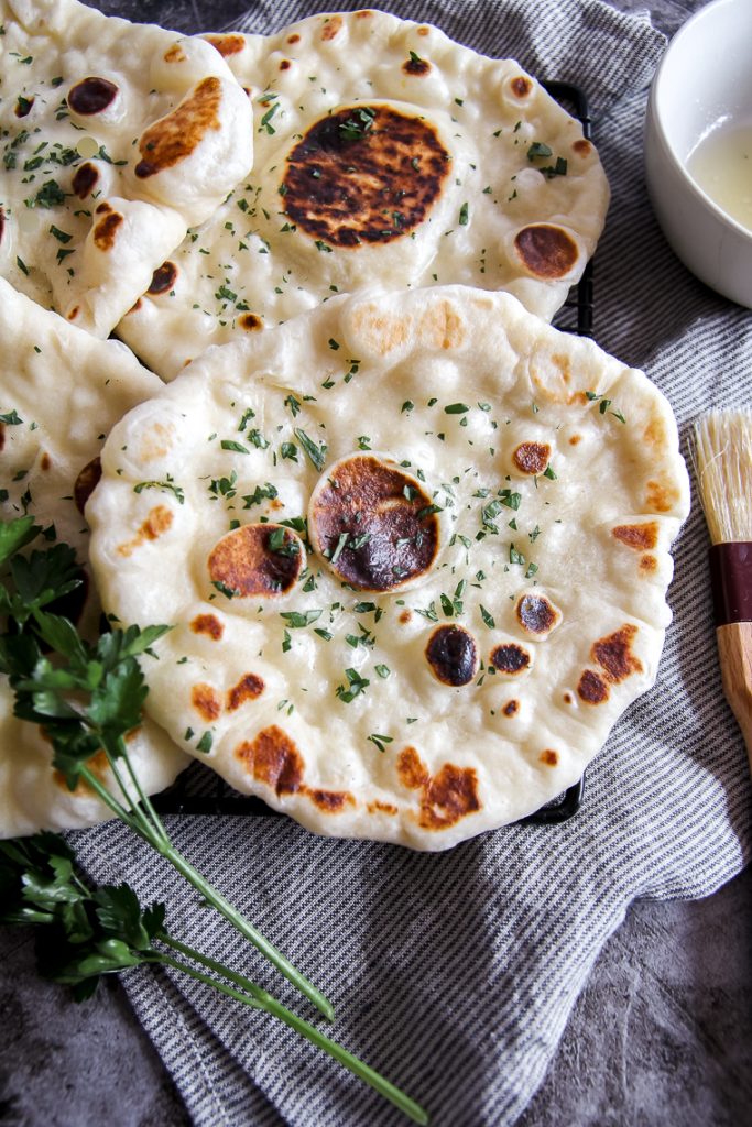 sourdough naan bread next to a pastry brush and melted butter