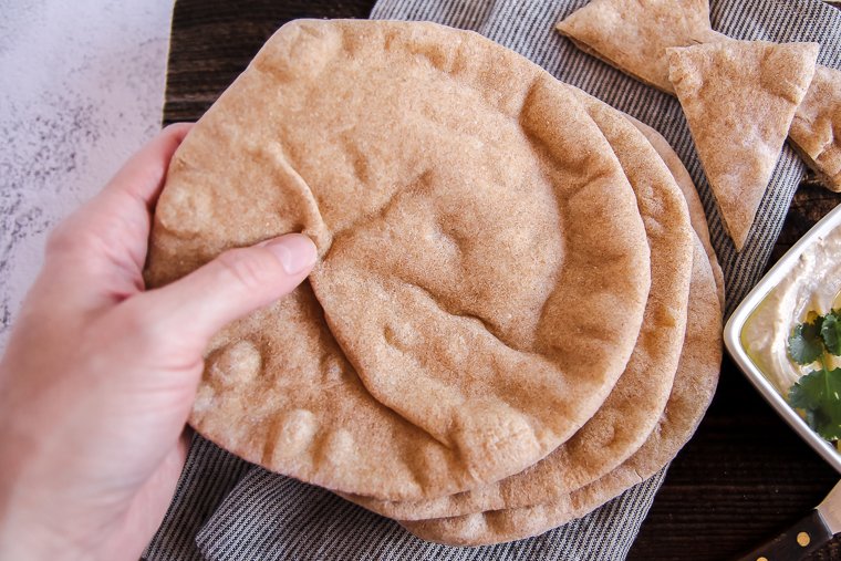 a hand grabbing a sourdough pita