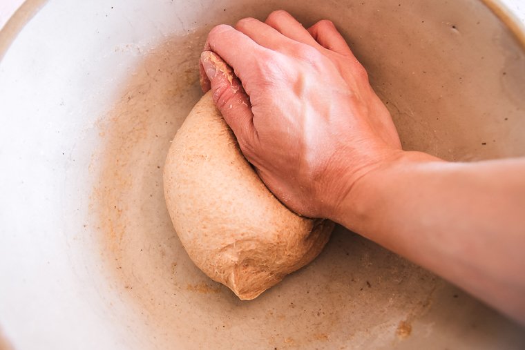 kneading the sourdough pita bread dough in a bowl