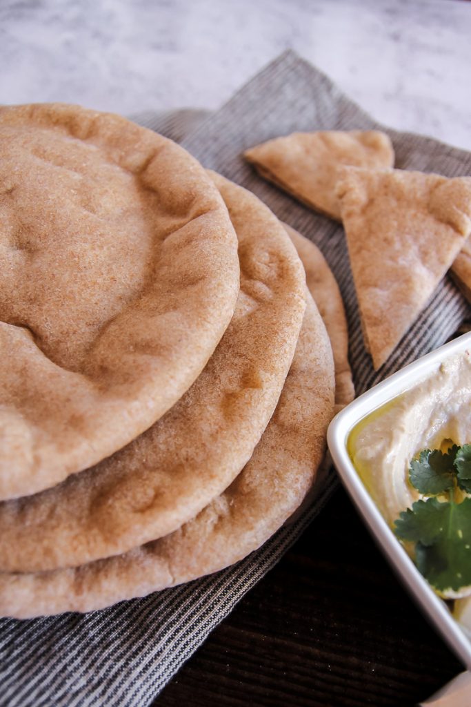 close up shot of sourdough pita on a board next to a dish of hummus