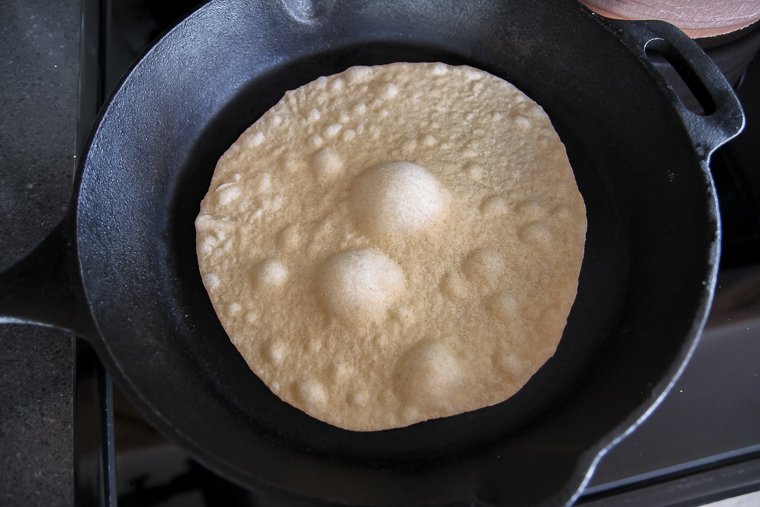 cooking a sourdough tortilla on a hot cast iron skillet and watching it bubble