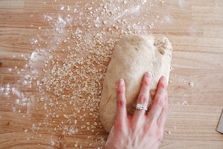 rolling a loaf through quick oats for a topping