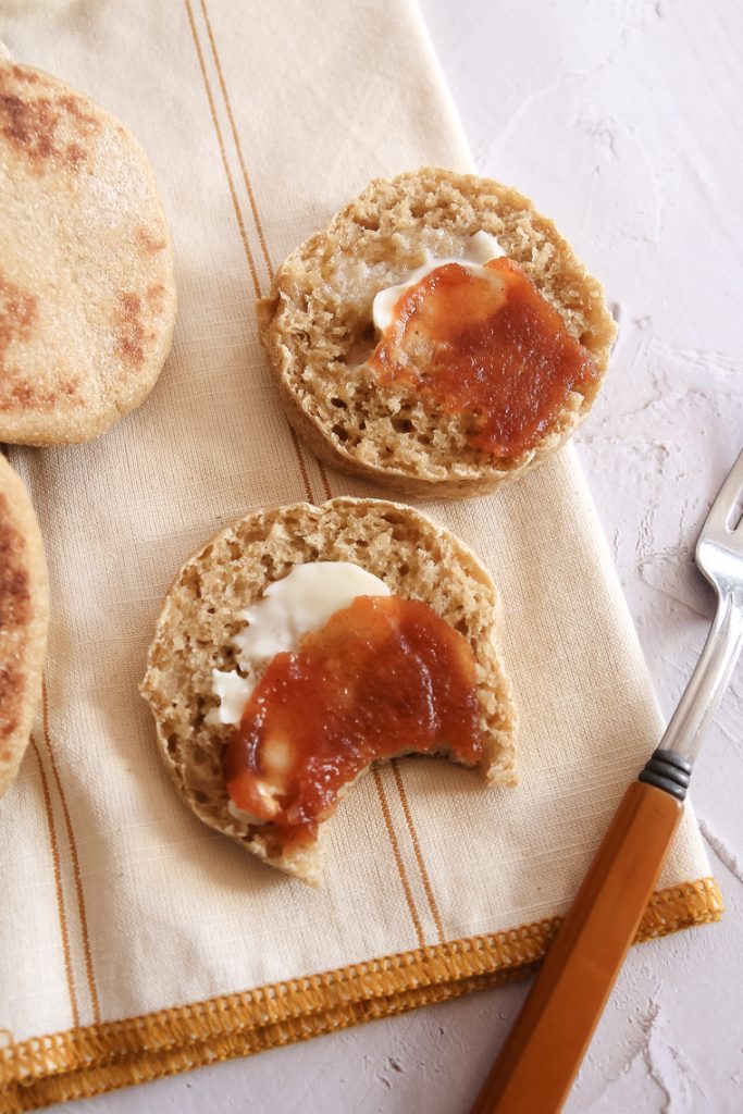 close up of a split whole wheat sourdough english muffin with butter and crabapple butter