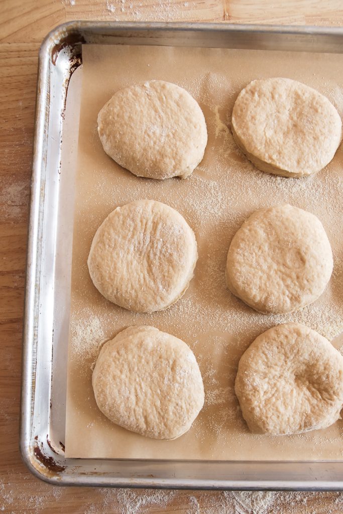 whole wheat english muffins on a prepared sheet pan after cutting