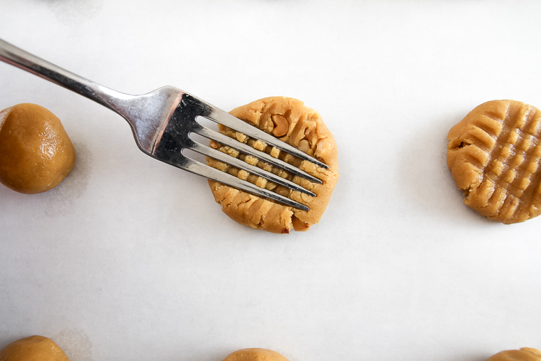 pressing the whole wheat peanut butter cookies with the tines of a fork