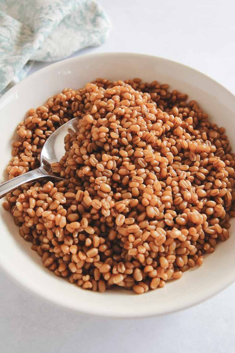 close up of cooked wheat berries in a bowl with a spoon