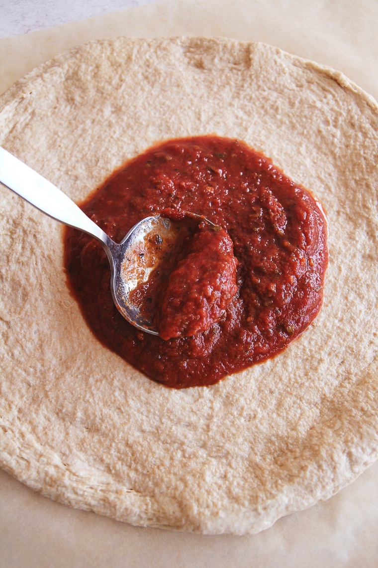 adding pizza sauce